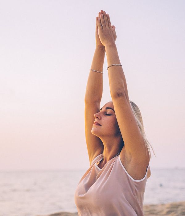 Person stretching peacefully outdoors during sunrise.